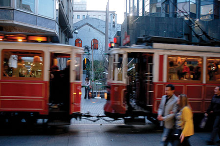 Light shines out from the open door of the Istanbul congregation's church, as a historic tram passes by in front. The church is located in a popular shopping area.