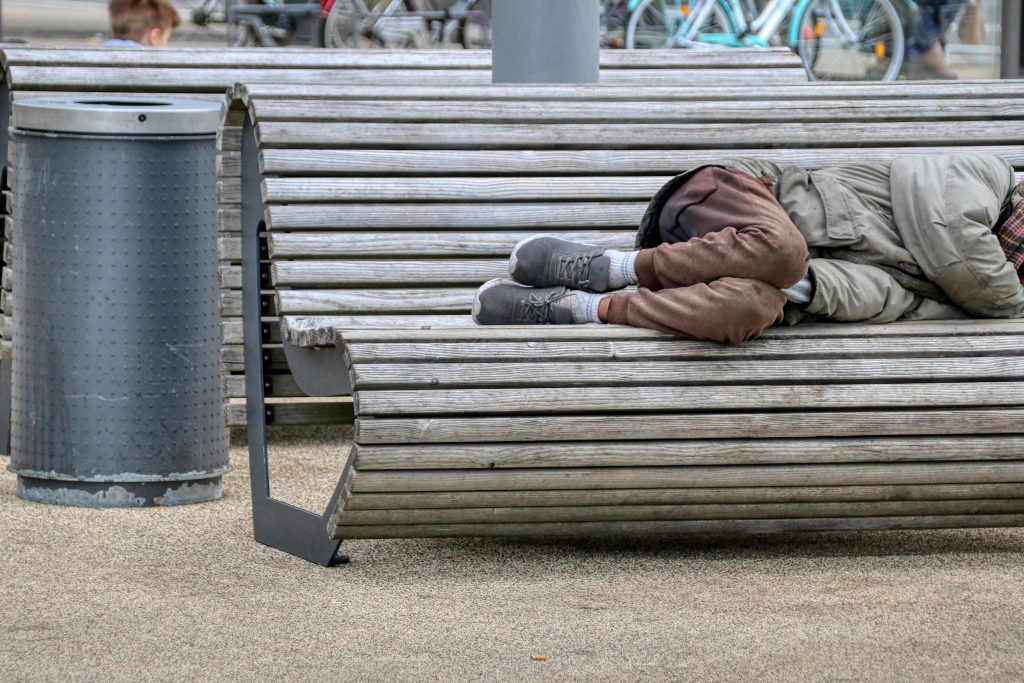 Homeless person sleeping on bench.