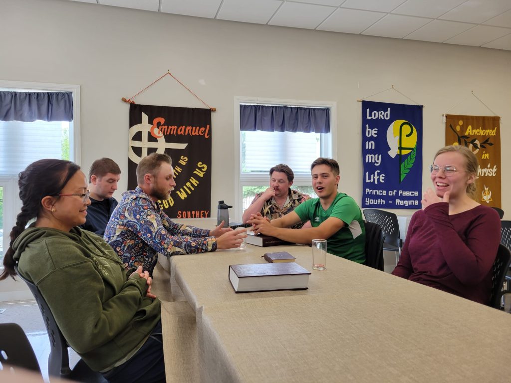 Young men and women sit around a table talking.